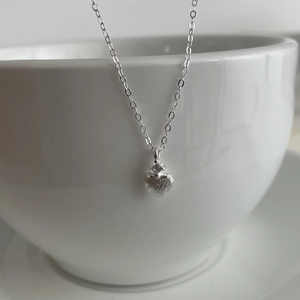 Dettaglio della collana cuore in argento S925 spazzolato con zircone su tazza di ceramica