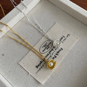 Elegante Muschel-Perlen-Halskette in Gold und Silber auf einem Segeltuch-Tablett