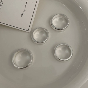 Detailed close-up of four thick polished silver rings set inside a white ceramic dish