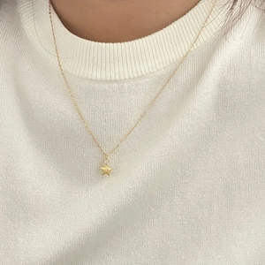 Elegant gold star necklace with shimmering zircon worn on a white knit sweater