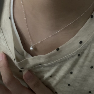 Primo piano della collana a cuore minimalista in argento S925 sulla clavicola lucida