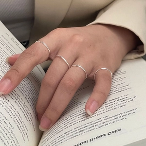 Minimalist S925 sterling silver thin stackable rings worn by a model over a book