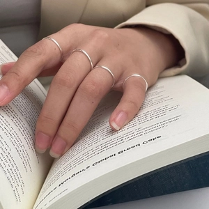 Close-up of minimalist S925 sterling silver thin rings stacked on woman fingers