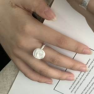 Détail d'une bague rose en argent sterling S925 portée au doigt sur fond texturé
