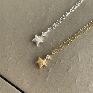 Macro detail of gold and silver brushed star pendants with sparkling cubic zirconia