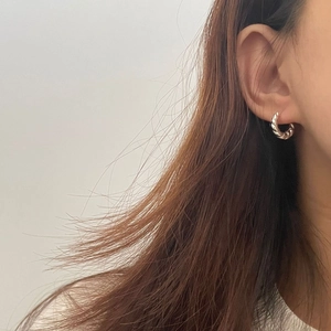 Vue latérale de créoles torsadées en argent portées par un mannequin pour un style chic