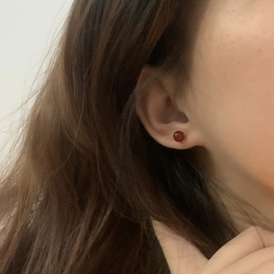 Close-up of minimalist round red agate stud earring worn on ear for elegant style