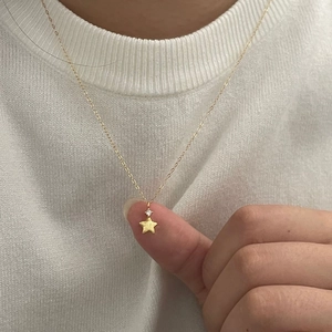 Close-up of gold brushed star pendant with cubic zirconia worn on a fine neck chain