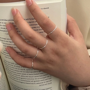 Close-up of minimalist S925 sterling silver stacked rings worn on fingers with a book