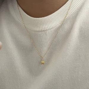 Close-up of a delicate gold S925 sterling silver star necklace on a woman neck