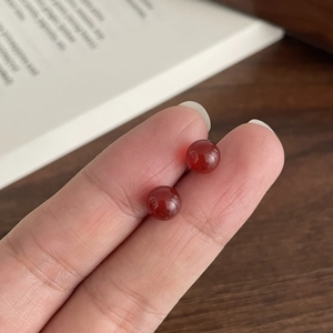 Macro shot of minimalist S925 silver stud earrings with 6mm red agate round beads