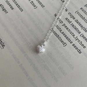 Dettaglio di una collana a cuore in argento S925 con texture spazzolata e zircone
