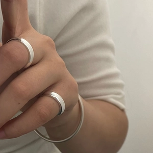 Close-up of polished S925 sterling silver minimalist rings and slim bangle set on hand