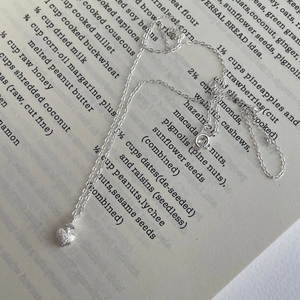Dettaglio della collana a cuore in argento S925 con zircone su pagina di libro vintage