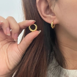 Détail de boucles d'oreilles créoles torsadées dorées avec un design en spirale