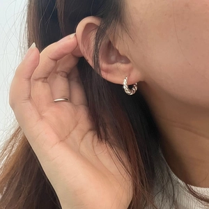 Gros plan de boucles d'oreilles créoles torsadées en argent S925 sur le mannequin