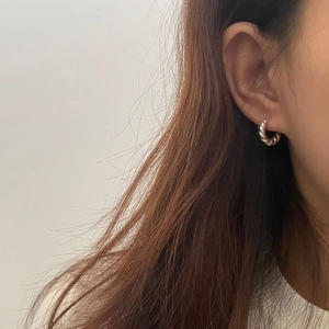 Détail de la boucle d'oreille créole torsadée en argent S925 sur modèle au style minimaliste