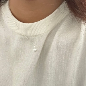 Close-up of S925 sterling silver star pendant necklace worn on a white knit sweater
