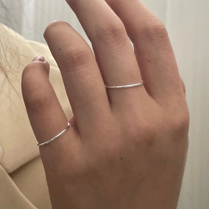 Detail view of minimalist thin S925 sterling silver bands worn on fingers for layering