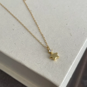 Detailed close-up of a gold star pendant with a sparkling zircon on a delicate chain