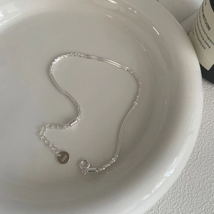 Macro view of S925 sterling silver chain with spring clasp on white ceramic