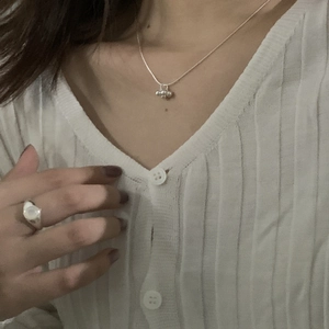Detail of S925 silver beaded cluster necklace and wide ring on a model in white knitwear