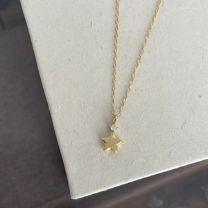 Detail shot of a golden star pendant necklace featuring a sparkling round zircon stone