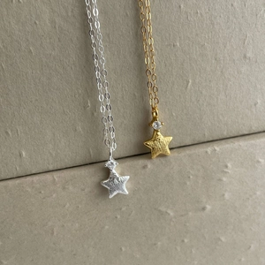 Macro detail of gold and silver S925 brushed star pendants with sparkling zircon stone
