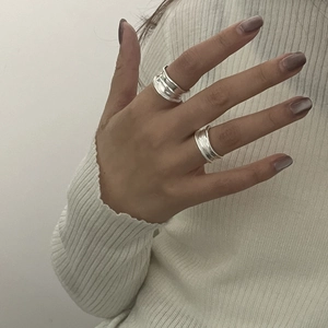 Detail view of two S925 sterling silver rings with irregular lava texture on fingers