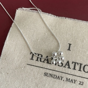 Detail of silver S925 beaded cluster pendant on a sleek snake chain necklace