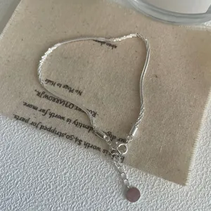 Detail of S925 sterling silver chain with lobster clasp and purity tag on linen