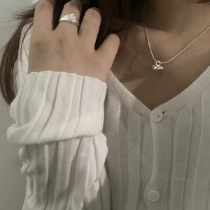 Detail of silver beaded necklace and minimalist ring with white gemstone on model