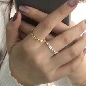 Dettaglio di anelli a doppia fila di perline in oro e argento per uno stile a strati