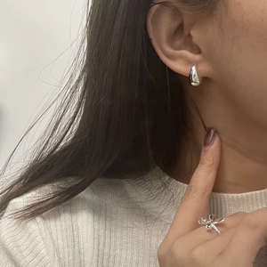 Detail view of 925 silver hollow teardrop earring and minimalist bow ring on model
