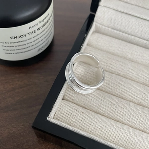 Detailed view of wide silver streamline ring on a beige jewelry display box texture