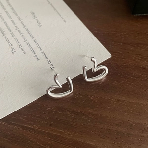 Macro shot of S925 sterling silver heart earrings on a minimalist wooden display