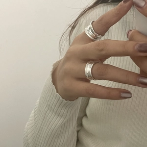 Detail view of stacked S925 sterling silver rings with irregular pleated texture on hand