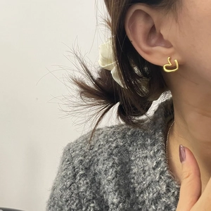Minimalist irregular hollow heart earrings in gold finish worn by a model in close-up view