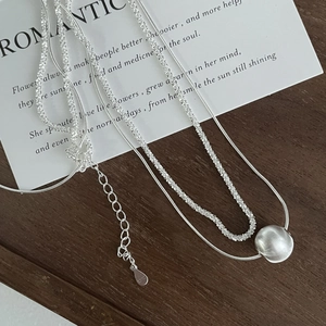 Détail du collier double couche en argent S925 avec pendentif boule en métal brossé