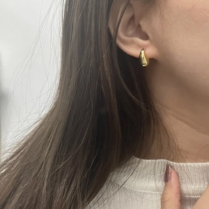 Close-up of elegant gold hollow teardrop earrings with a polished mirror finish on model
