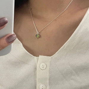 Close-up of 925 sterling silver necklace with a green zircon oval pendant worn on neck