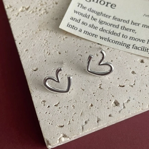 Artistic close-up of minimalist S925 sterling silver irregular heart-shaped stud earrings