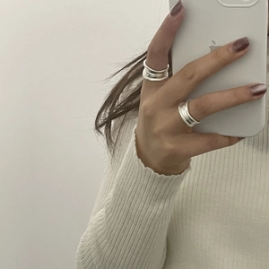 Detail of stacked silver wave textured rings on fingers with adjustable open band design