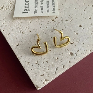 Detailed macro shot of irregular hollow heart stud earrings on stone background