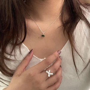Close-up of 925 silver necklace with green oval gemstone and bow-shaped open ring