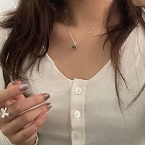 Detail of S925 silver necklace with green round gemstone pendant on a female model