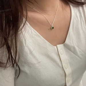 Close-up of model wearing 925 silver necklace with green gemstone pendant on neck