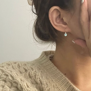 Close-up of S925 sterling silver hook earrings with round light blue moonstone drop