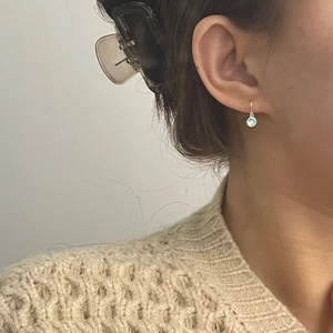 Detailed close-up of a sterling silver drop earring with a clear light blue gemstone