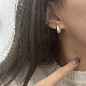 Close-up of polished 925 sterling silver hollow teardrop earrings worn on ears